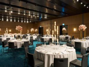 a banquet hall with white tables and chairs and chandeliers at Novotel Melbourne Airport in Melbourne +102 photos