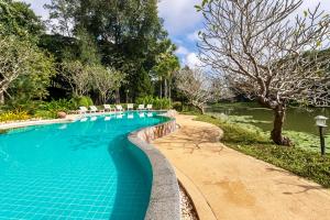 a swimming pool with chairs next to a lake at Lampang River Retreat in Lampang