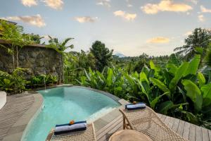 een zwembad van het resort met ligstoelen en uitzicht op de bergen bij Govala Usada Ubud Villa in Ubud