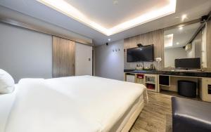 ein Schlafzimmer mit einem großen weißen Bett und einem Fernseher in der Unterkunft Spa Tower Motel in Daejeon