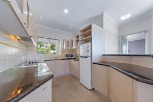 een keuken met witte kasten en een witte koelkast bij Spa Haven 18A in Airlie Beach