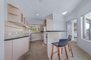 een keuken met witte kasten en een tafel en stoelen bij Spa Haven 18A in Airlie Beach