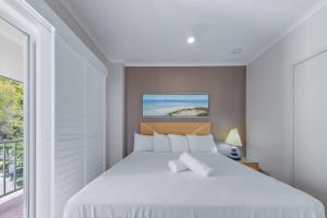 een slaapkamer met een wit bed en een balkon bij Spa Haven 18A in Airlie Beach +16 foto's