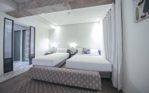 two beds in a hotel room with a couch at BROWN DOT Hotel Dadaepo Beach in Busan