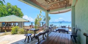 una terrazza in legno con tavoli, sedie e vista sull'oceano di Morning Walsh Resort El Nido a El Nido
