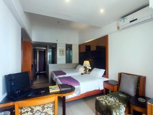 une chambre d'hôtel avec un lit et un bureau avec un ordinateur dans l'établissement Ming Yang Hotel, à Haikou