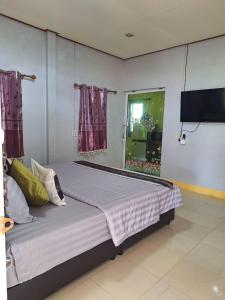 ein Schlafzimmer mit einem großen Bett und einem Fernseher an der Wand in der Unterkunft Baan Suan Thada Thai บ้านสวนธาดา ไทย in Wang Nam Yen