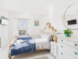 een witte slaapkamer met een bed en een spiegel bij The Boathouse in Torquay