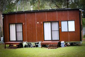 a red building with windows and tables and chairs at The Glan Devon Tiny Retreat in Glan Devon