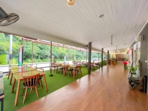 ein Esszimmer mit Tischen, Stühlen und Fenstern in der Unterkunft Royal Hill Satun Hotel in Ban Pak Ba Ra