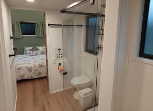 a bathroom with a shower and a toilet and a bed at The Glan Devon Tiny Retreat in Glan Devon