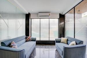ein Wohnzimmer mit zwei blauen Sofas und einem großen Fenster in der Unterkunft Townhouse Sector 49 Gurugram Formerly Hotel P66 in Gurgaon