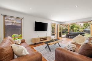 een woonkamer met twee banken en een flatscreen-tv bij Barramundi Beach House in Smiths Beach