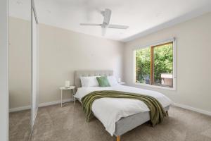 een witte slaapkamer met een bed en een raam bij Barramundi Beach House in Smiths Beach