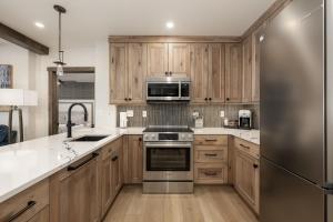 a kitchen with wooden cabinets and a stainless steel refrigerator at Select Unit 2509 - Zephyr Mountain Lodge condo in Winter Park