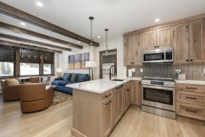 a kitchen with wooden cabinets and a living room at Select Unit 2509 - Zephyr Mountain Lodge condo in Winter Park +8 photos