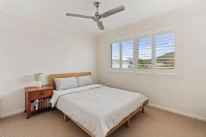 een witte slaapkamer met een bed en een raam bij Caba Coast Retreat in Cabarita Beach +12 foto's