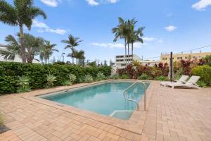 een zwembad met 2 stoelen en palmbomen bij Caba Coast Retreat in Cabarita Beach