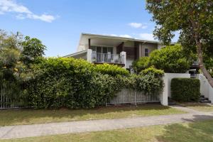 een wit huis met een hek en struiken bij Caba Coast Retreat in Cabarita Beach