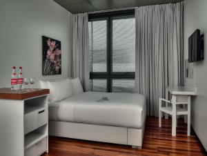 a bedroom with a bed and a desk and a window at rõõm collective in Odiongan +4 photos