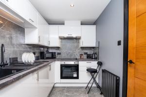 a kitchen with white cabinets and a black counter top at The Apartment in Paisley +10 photos