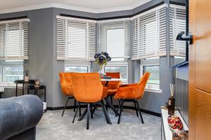 a dining room with orange chairs and windows at The Apartment in Paisley