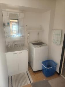 uma pequena cozinha branca com um lavatório e uma máquina de lavar roupa em 古民家宿懐 em Nachikatsuura