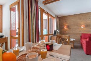 a living room with a couch and a table with food at Residence Les Chalets des Arolles - maeva Home in Mâcot La Plagne