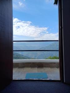 een deur die toegang geeft tot een groot raam met uitzicht bij Jun Homestay in Kalimpong