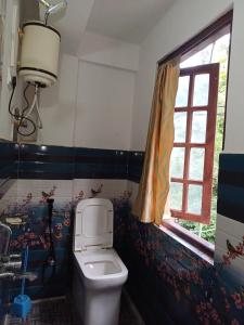 een badkamer met een toilet en een raam bij Jun Homestay in Kalimpong