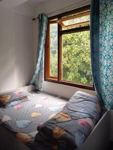 een kleine slaapkamer met een bed en een raam bij Jun Homestay in Kalimpong