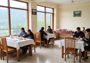 eine Gruppe von Menschen, die an Tischen in einem Restaurant sitzen in der Unterkunft Kanara Hotel in Bhīm Tāl + 16 Fotos