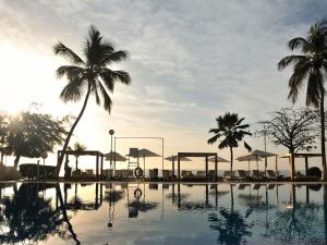 ein Pool mit Palmen und ein Volleyballfeld in der Unterkunft Pullman Dakar Teranga in Dakar