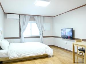 束草市Sorak Y Hostel的一间带床、桌子和电视的卧室