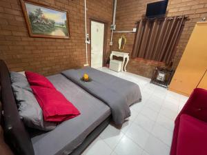 a large bed with red pillows in a room at บ้านมาดาม เขาใหญ่ in Pak Chong