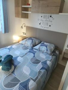 Bett mit blauer und weißer Decke in einem Zimmer in der Unterkunft Camping Siblu Bella Vita in Canet-en-Roussillon