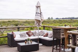 a patio with a couch and an umbrella on a deck at Thali Thali Game Lodge in Langebaan