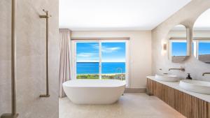 a bathroom with two sinks and a large window at 'Ocean Pearl' by HolidayCo in Hardys Bay