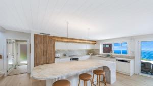 a kitchen with a large island with stools at 'Ocean Pearl' by HolidayCo in Hardys Bay +16 photos