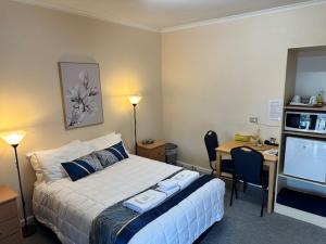 een slaapkamer met een bed, een bureau en een televisie bij Bamboo Motor Inn in Lakes Entrance