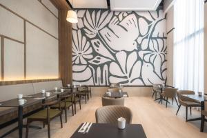 a restaurant with tables and chairs and a mural at Hyatt Place Cancun Airport in Cancún