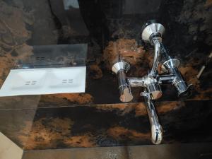 a bathroomaucet with a sink and a mirror at Nisarga Comforts in Chikmagalūr