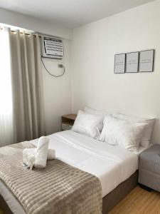 a bedroom with a large white bed and a window at EasyStay Condo Davao in Davao City +11 photos