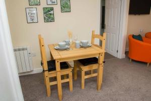 a wooden table with two chairs and a table with cups at Orange Lilly in Stroud with Free Parking in Stroud