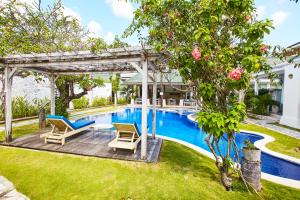 a backyard with a pool and two chairs and a pergola at M-Apartment in Badung
