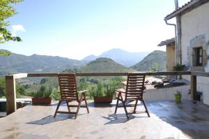 2 Stühle auf einem Balkon mit Bergen im Hintergrund in der Unterkunft La Terraza de Onís in Bobia de Arriba