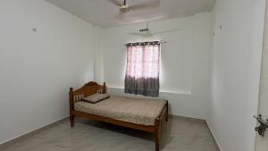 un petit lit dans une chambre blanche avec une fenêtre dans l'établissement Budget Non AC Room beside Kolencherry MOSC Hospital, à Kadayirippu