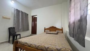 une chambre avec un lit et une chaise dans l'établissement Budget Non AC Room beside Kolencherry MOSC Hospital, à Kadayirippu
