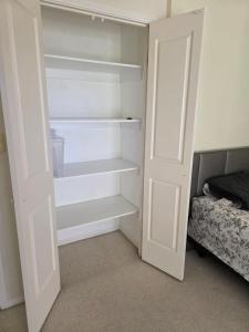 a white closet with a door open next to a bed at Gaven Garden in Gold Coast