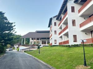 ein großes weißes Gebäude mit einem Rasenhof neben einer Straße in der Unterkunft Belle Villa Resort, Chiang Mai in Ban Pong